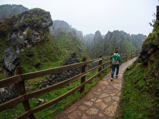 Fototapeta na wymiar Joven camina por un camino de piedra entre los riscos del Parque natural de los Picos de Europa.