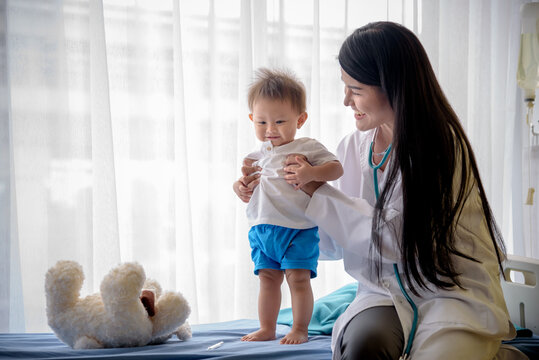 Portrait images of Asian Gynecologist or woman doctor and a 1 year old boy patient on a Patient bed, They are happy to recover from their illness, to people and health care concept.