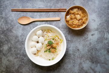 Rice stick noodles with fish ball and garlic cracklings with lard in white bowl. 