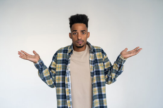 Portrait of young african american man gesturing do not know sign with confused expression isolated on white background