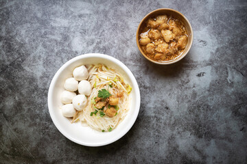 Rice stick noodles with fish ball and garlic cracklings with lard in white bowl. 