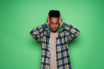 African american man with green shirt having doubts while scratching head isolated on green background