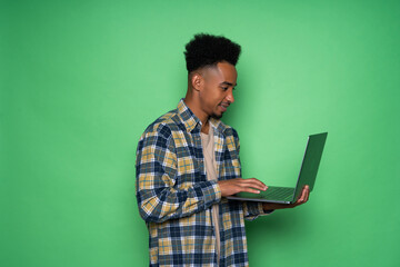 Young african man holding laptop isolated on green background