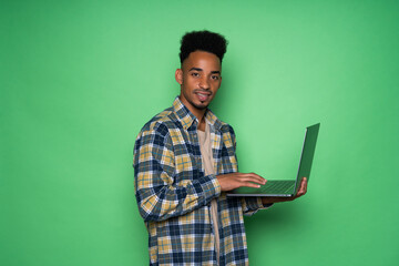 Young african man holding laptop isolated on green background
