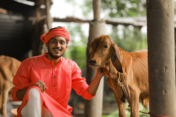 Young indian farmer with his cow at dairy farm
