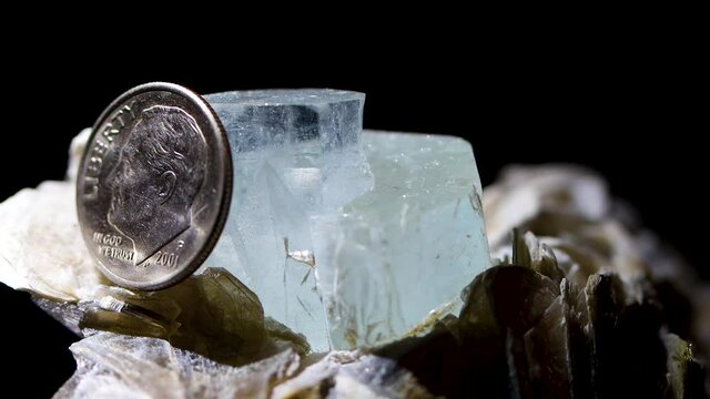 A tight detail shot of an aquamarine crystal in a muscovite matrix using a dime as a reference for size. Found in the hills of Argentina.