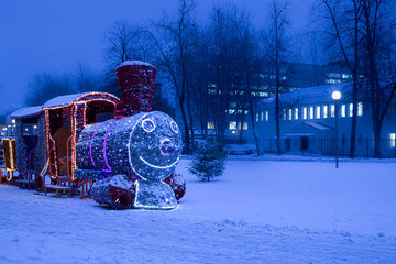 Naklejka premium New year's train with lighting on a snowy winter evening in the city.