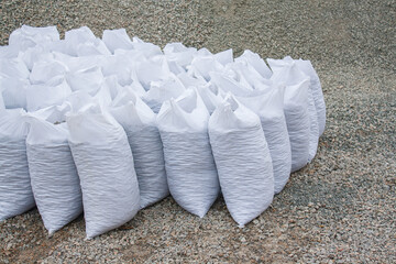 white bags of crushed stones are in a row against a background of rubble, building material in the...
