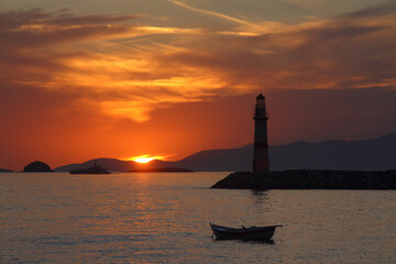 Fototapeta premium Seascape at sunset. Lighthouse on the coast. Seaside town of Turgutreis and spectacular sunsets