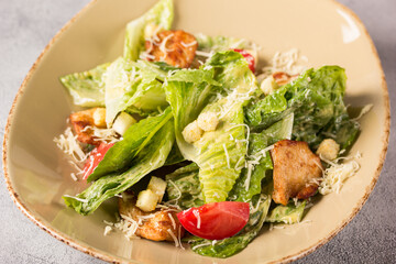 Caesar salad with chicken. Romano lettuce, chicken fillet, tomatoes, croutons, parmesan cheese and sauce in a plate on a light background. Restaurant menu. Background image, copy space