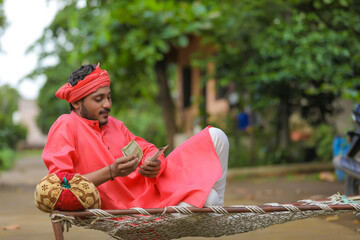 young indian farmer counting money at home