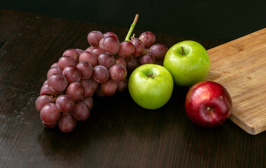 fruit still life with grapes and green and red apple on a black background