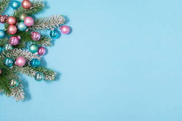 Christmas tree branches with pink and blue decoration balls flat lay frame with copy space