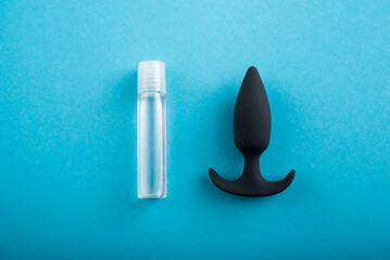 Top view of black anal plug and tube of lubricant on a blue background