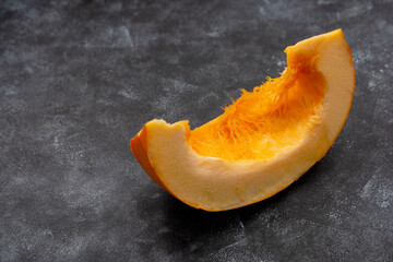Piece of pumpkin isolated on dark background, fall food. Copy space.