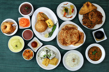 Assorted indian food on wooden background. Dhokla,kachori,samosa,vada,jalebi,jamun,paneer butter masala,poori,curd vada.. Dishes and appetizers of indian cuisine