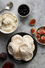 Cooking dessert. Abstract food background. Top view of mini Pavlova meringue cakes decorated with berries and figs.