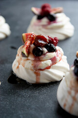Mini Pavlova meringue cakes decorated with berries and figs.