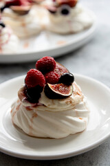 Mini Pavlova meringue cakes decorated with berries and figs.