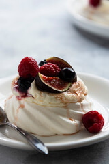 Mini Pavlova meringue cakes decorated with berries and figs.