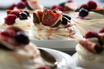 Mini Pavlova meringue cakes decorated with berries and figs.