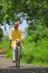 Young indian farmer or labor going to work by cycle