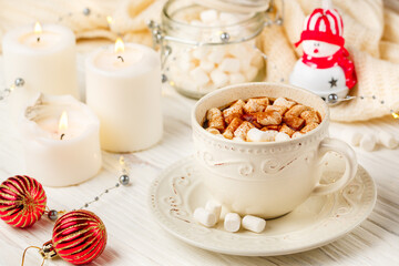 Coffee, cocoa, hot chocolate with marshmallows and cinnamon in a white Cup on a wooden table. New year. The concept of comfort and relaxation with candles, spices and Christmas toys. Selective focus