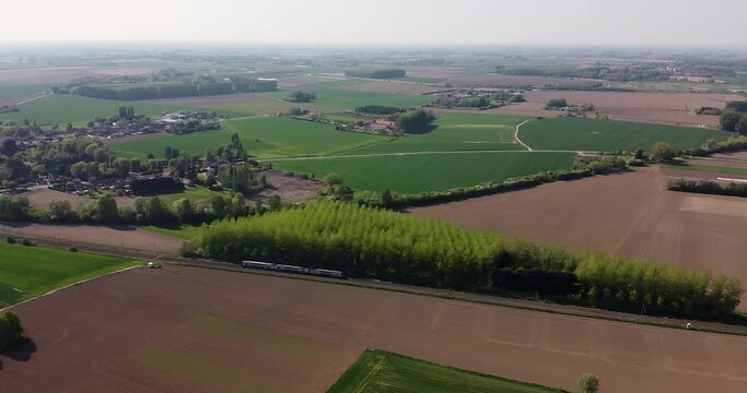 Vue a&eacute;rienne du passage d'un train sur une ligne de chemin de fer entour&eacute;e de champs et d'arbres. Wavrin, Nord, Hauts-de-France, France.