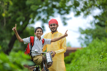 Young indian farmer and his son going to school on cycle