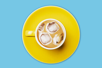 Ice coffee top view. Frozen latte with ice cubes. Yellow ceramic cup on yellow ceramic plate. Sweet sugar beverage milk drink.