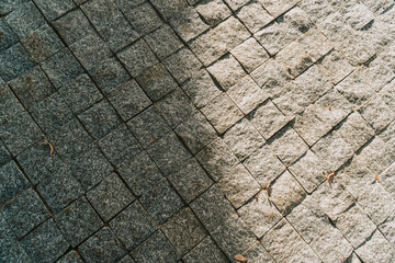 Grey stone pavement texture. Paving stones with yellow autumn leaves