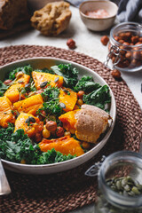 Season salad with grilled pumpkin, kale, chickpea, pepitas and nuts. Autumn vegetarian healthy recipe.