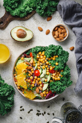 Obraz na płótnie Canvas Healthy vegetarian salad with avocado, chickpea, fresh kale, romano leaf, cherry tomatoes, almond. onion and orange.