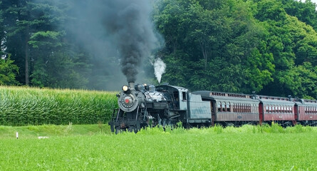 Fototapeta na wymiar Antique Steam Passenger Train Puffing along Amish Countryside with Green Fields
