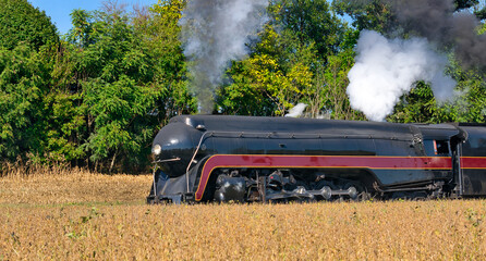 Fototapeta na wymiar Close up of an Antique Steam Freight Train Puffing Smoke and Steam While going Thru Amish Countryside