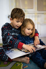 Brother and sister read book in pajamas bare feet evening sleep family