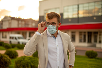 Young businessman standing at the front of the clinic with a face mask protection.