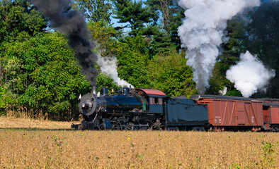 Obraz na płótnie Canvas Close up of an Antique Steam Freight Train Puffing Smoke and Steam While going Thru Amish Countryside