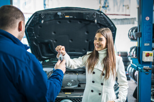 A Female Client Giving Keys To Car Mechanic In The Garage