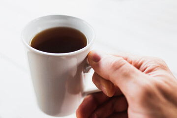 White cup of black aromatic coffee in hand - morning vigor
