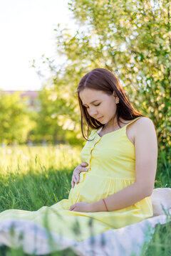 pregnant woman with big belly sitting on grass in Park