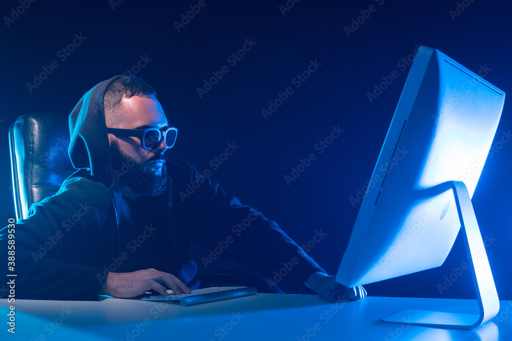 Poster programmer next to computer. man in sunglasses works in the dark. concept - guy works as a web progr