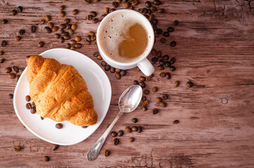 a white cup
cappuccino, croissant and coffee beans on brown wooden retro background, selective focus. Breakfast concept