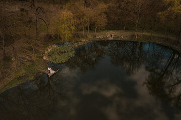 married couple a man with a pregnant woman with a big belly stand on a wooden bridge on coast lake river in nature. Aerial drone top view