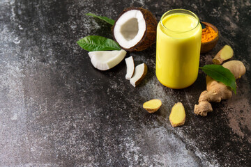 Healthy drink. Ayurvedic golden coconut milk with curcuma powder ginger on a stone countertop. Copy space.