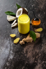 Healthy ayurvedic drink golden coconut milk with curcuma powder ginger on a stone countertop. Copy space.