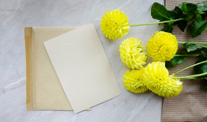 Greeting, post card, invitation card with craft folder. Photo mock up on marble background with yellow chrysanthemum bouquet.