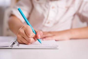 Close up of child's hand making notes in the writing pad lying on the diagrams