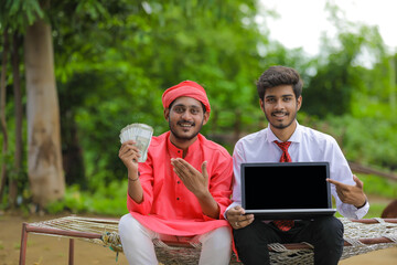 Fototapeta premium Young indian farmer showing indian rupees with bank officer at home