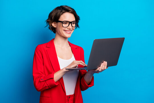 Portrait of attractive busy focused intelligent cheerful lady assistant holding in hand laptop typing isolated bright blue color background